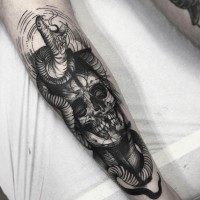 Langer schwarzer beschädigter Schädel Tattoo am Unterarm mit wütender Schlange