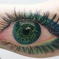 Lovely green eye with green makeup tattoo on arm by cris gherman