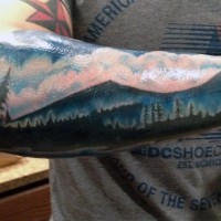 Tatuaje en el antebrazo, montañas  y bosque impresionantes