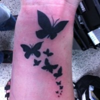 Tatuaje en la muñeca, bandada de mariposas negras
