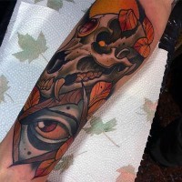 Tatuaje en el antebrazo,
 cráneo de animal con hojas y ojo misterioso
