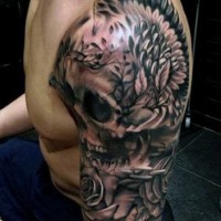 Tatuaje en el brazo, cráneo enorme con alas de águila y flores