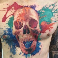 Tatuaje en el pecho, 
cráneo sonriente con manchas de pintura multicolores