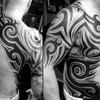 Massive black and white tribal tattoo with lettering on chest, shoulder and side