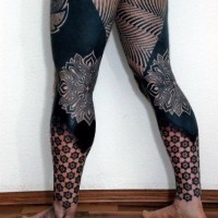 Massive black ink detailed identical tribal tattoos on legs combined with big flowers