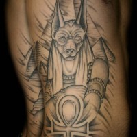 Tatuaje en el costado, dios Anubis y pirámides, dibujo simple negro blanco