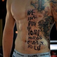 Massives farbiges Tattoo an der halben Brust mit Monstergesicht und Schriftzug