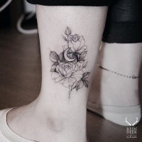 Medium size blackwork style ankle tattoo by Zihwa of flowers with moon