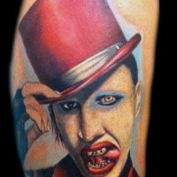 Merlin Manson in red hat liking lips colored portrait tattoo in realism style