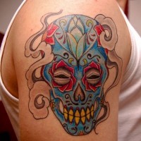 Mexican native multicolored smiling skull tattoo on shoulder zone