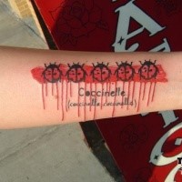 Modern style colored forearm tattoo of ladybugs with lettering