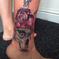 Modern traditional style colored ankle tattoo of human skull with rose and lettering