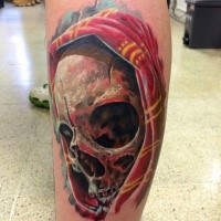 Modern traditional style colored leg tattoo of human skull with hood
