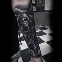 Mystical illustrative style black ink forearm tattoo of human skeleton in hood