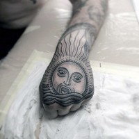 Tatuaje en la mano, sol con cara en ondas, estilo tribal