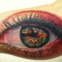 Naked girl in pupil of eye tattoo on arm