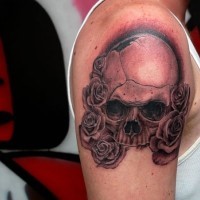 Natural looking accurate painted black ink broken skull tattoo on shoulder with rose flowers