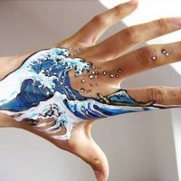 Natürlich aussehende schöne Aquarell Wellen Tattoo an der Hand mit Insel