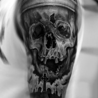 Tatuaje en el brazo, cráneo humano grande y cementerio oscuro