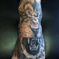 Natural looking black and white roaring lion tattoo on foot