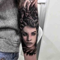 Natural looking black ink seductive Medusa head tattoo on arm