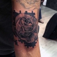Natural looking colored arm tattoo of human hand with rose flower and puzzle