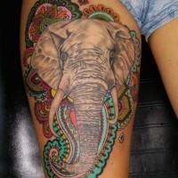 Natural looking colored elephant tattoo on thigh combined with Hinduism themed ornaments