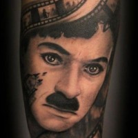 Tatuaje en el antebrazo, retrato de  Charlie Chaplin precioso con carrete de película