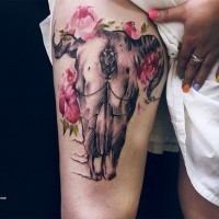 Natural looking colored thigh tattoo of animal skull with flowers