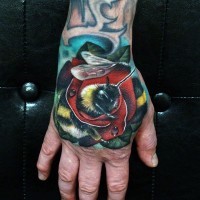 Tatuaje colorido de  abeja en flor en la mano