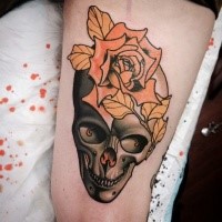 Neo traditional colored thigh tattoo of human skull with big flower