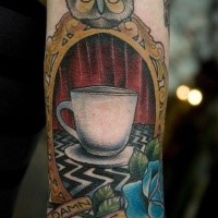 New school style colored arm tattoo of cup portrait stylized with owl and lettering
