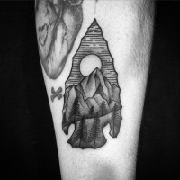 Nice 3D like black ink ancient arrow head tattoo on forearm stylized with mountains