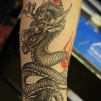 Tatuaje en el antebrazo, dragón chino gris con cintas rojas