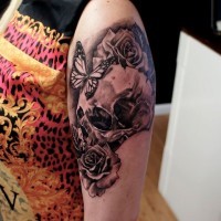 Nice looking black ink skull with flowers tattoo stylized with butterflies