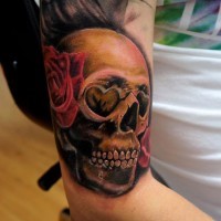 Nice looking colored human skull tattoo on arm with rose