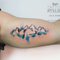 Nice mountain scenery tattoo on biceps by Julia Dumps with watercolor details