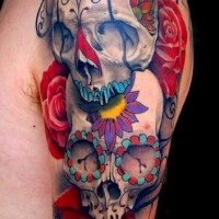Tatuaje en el brazo, cráneos abigarrados con flores diferentes