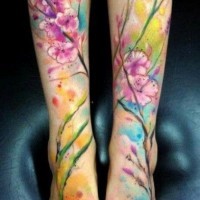 Tatuaje  de flores y ramita de acuarelas en las piernas