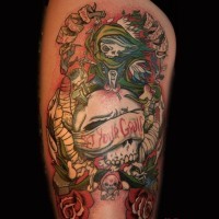 Old cartoon style colored evil witch with skull and lettering tattoo on thigh