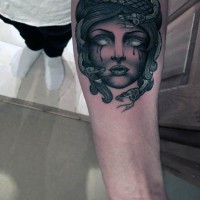 Old cartoon style painted and colored crying Medusa head tattoo on arm