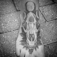 Old looking dot style foot tattoo of animal skull with moon ornaments