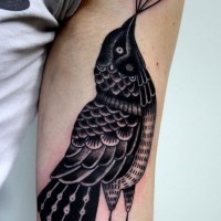Tatuaje negro blanco en el brazo,
cuervo estilizado con figura geométrica, estilo old school