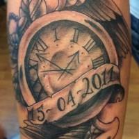 Oldschool schwarze Denkmal Uhr Tattoo am Unterarm mit Flügeln und Datum