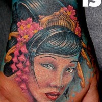 Old school cartoon like colored hand tattoo of beautiful Asian woman with flowers in hair