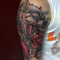 Old school colored big evil wolf on shoulder tattoo stylized with bird and flowers