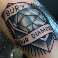 Tatuaje en el brazo,
 diamante en ataúd y cinta con frase