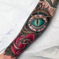 Old school colored mystical compass with eye tattoo on forearm with red rose