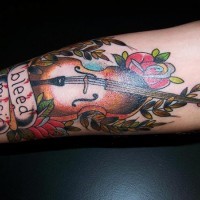 Tatuaje en el antebrazo, violín con flores y inscripción, old school