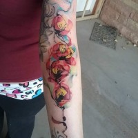 Old school homemade like colored flowers tattoo on forearm